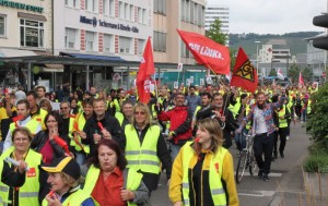 Müllerschön mit IG Metall-Fahne, Vollert mit der Fahne der LINKEN inmitten der Demonstration.
